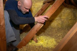 Home inspector inspecting condition of home attic and finding moisture on the ceiling.
